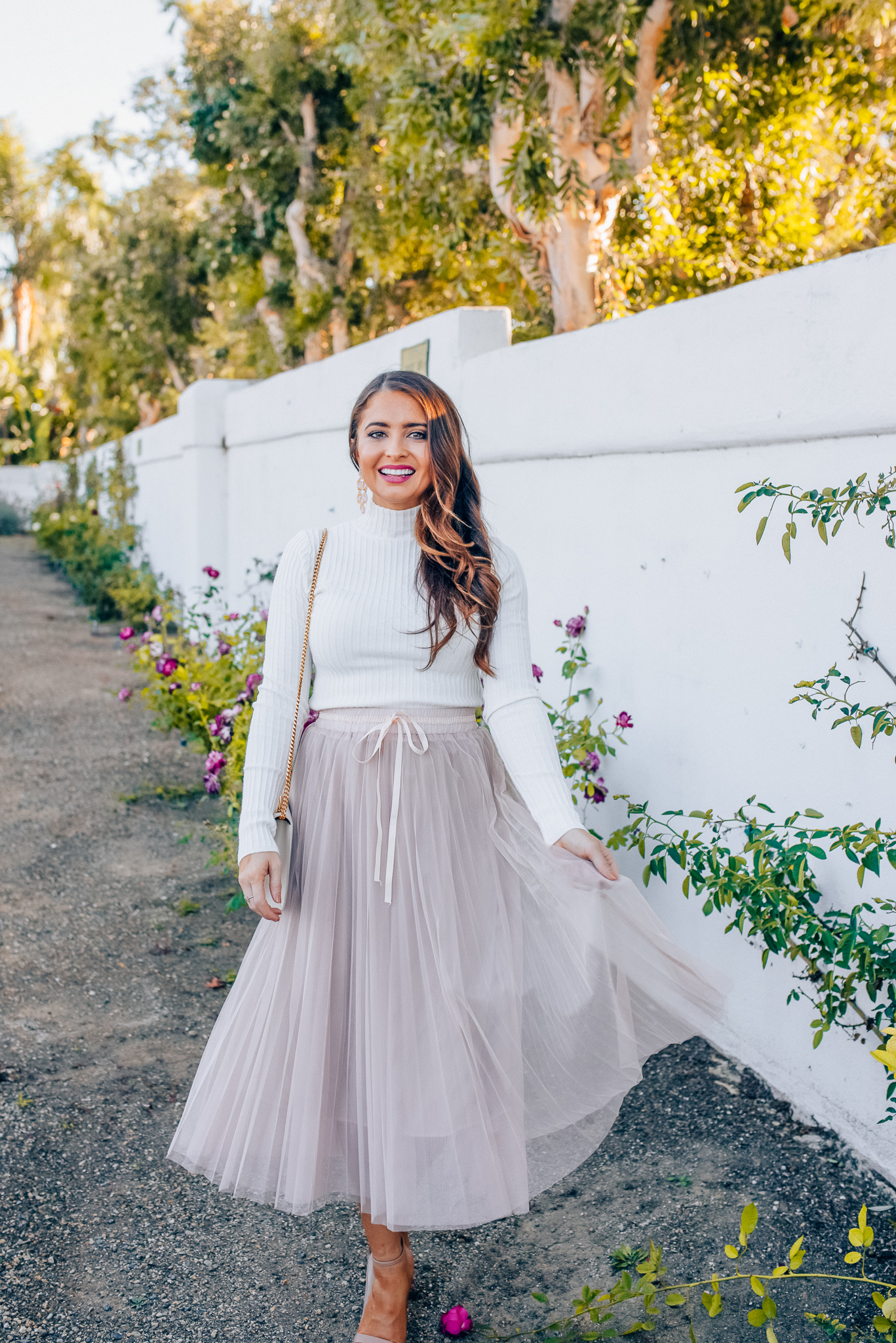 Tips to style a layered tulle skirt featured y top Los Angeles fashion blogger, Maxie Elise: image of a woman wearing a Chicwish long tulle skirt, Forever 21 cream turtleneck, Lisi Lerch earrings and Steve Madden sandals 