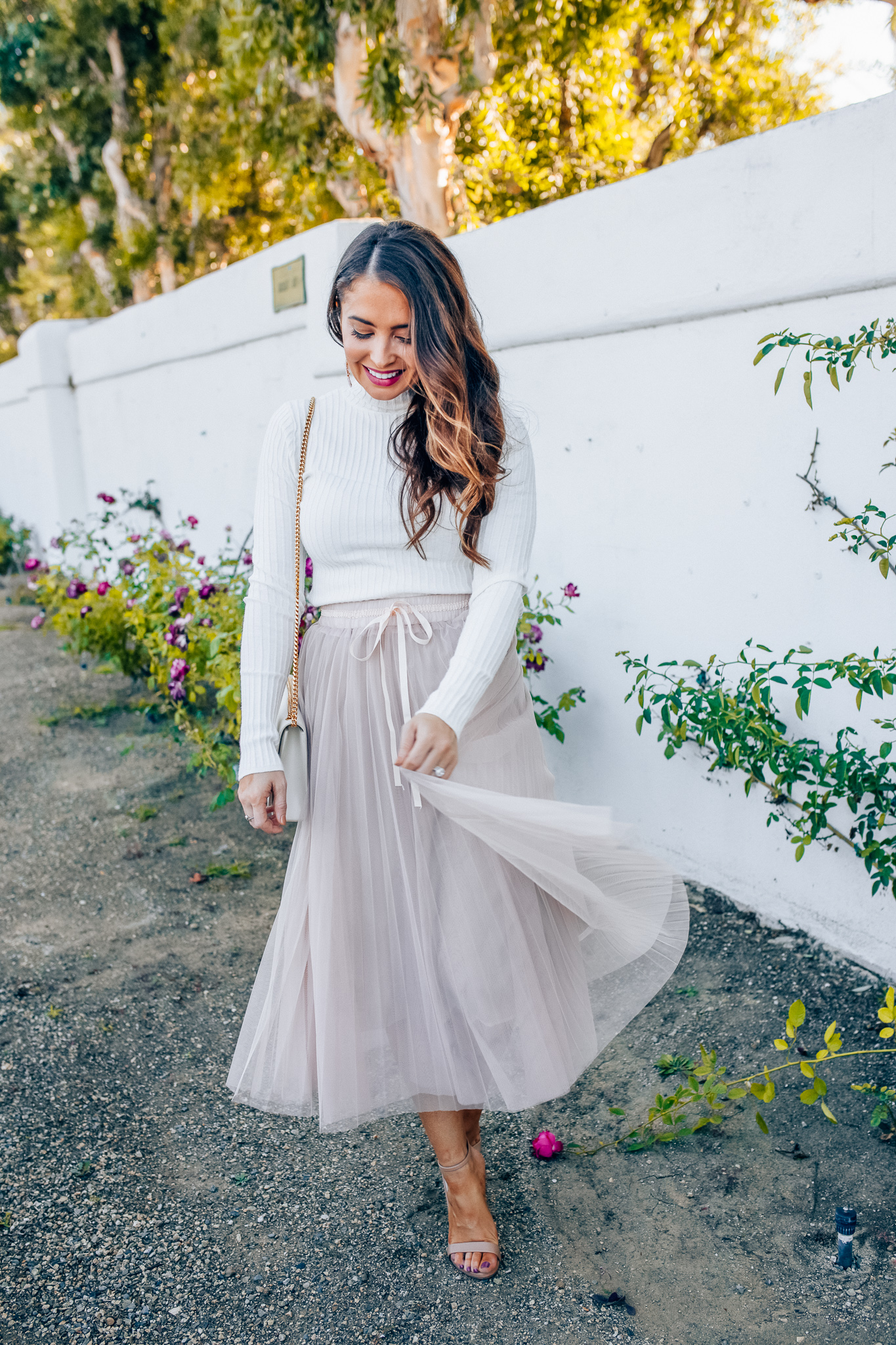 Tips to style a layered tulle skirt featured y top Los Angeles fashion blogger, Maxie Elise: image of a woman wearing a Chicwish long tulle skirt, Forever 21 cream turtleneck, Lisi Lerch earrings and Steve Madden sandals