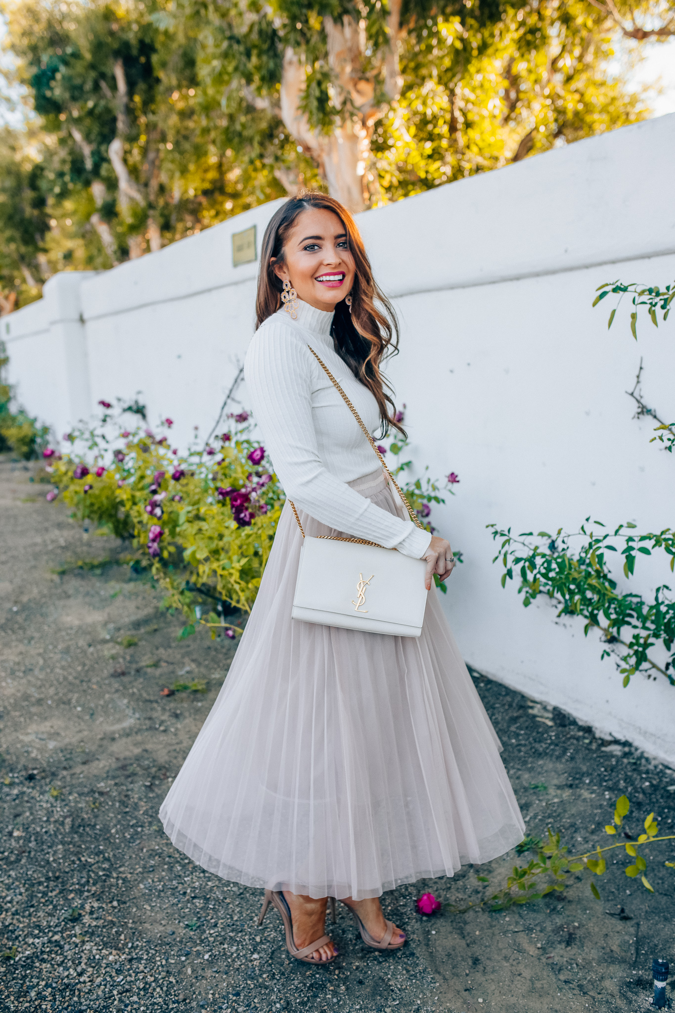 Tips to style a layered tulle skirt featured y top Los Angeles fashion blogger, Maxie Elise: image of a woman wearing a Chicwish long tulle skirt, Forever 21 cream turtleneck, Lisi Lerch earrings and Steve Madden sandals 