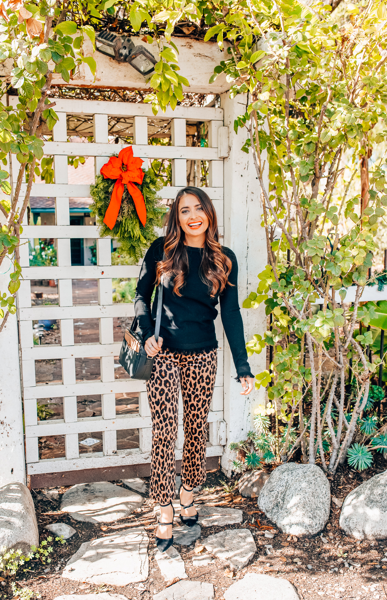 Leopard Holiday style featured by top Orange County fashion blogger, Maxie Elle: image of a woman wearing an Ann Taylor black fringe sweater, Ann Taylor leopard velvet pants, and Ann Taylor camera bag