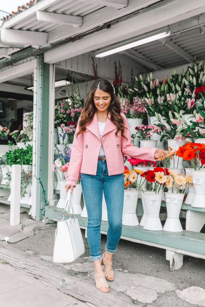 brunette girl in front of flower shop in pink coat