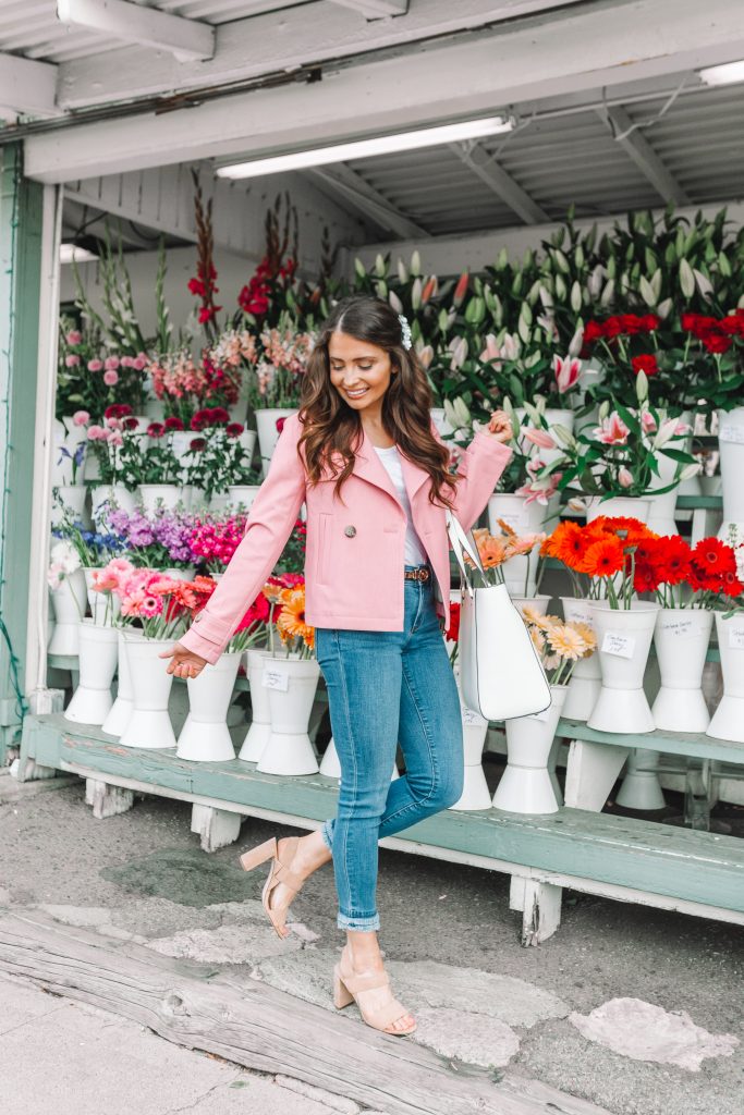 brunette girl in front of flower shop in pink coat