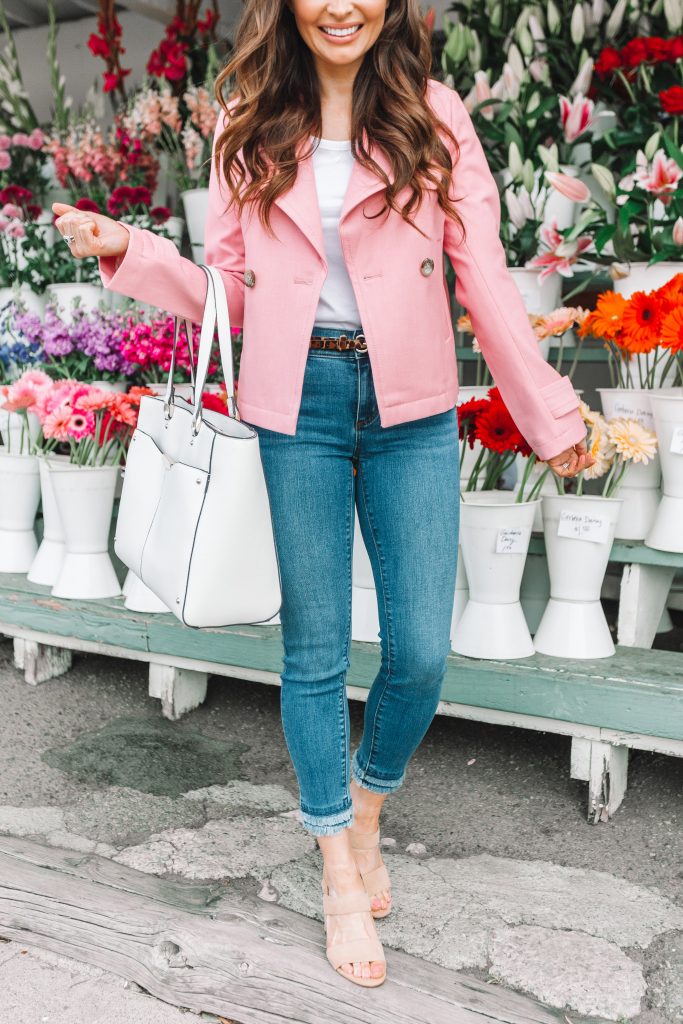 girl holding white bag wearing pink jacket and jeans
